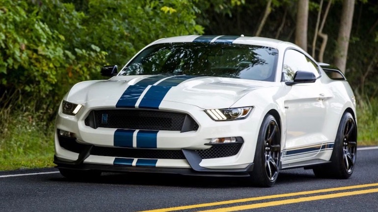 Ford Mustang GT350R A white street racing car with blue racing strip on a country road speeding along.