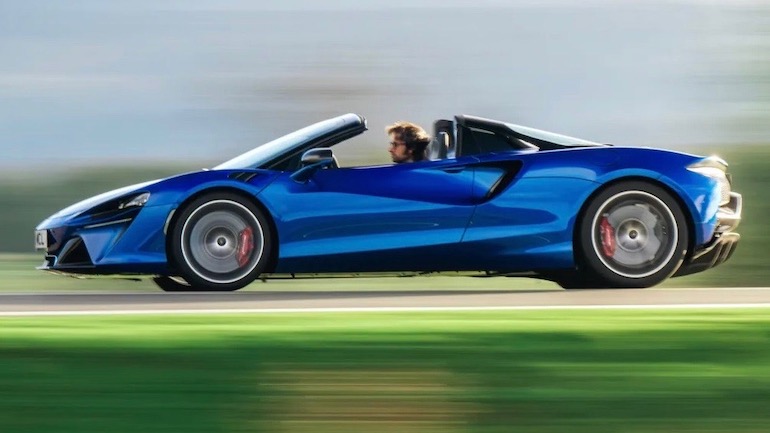 McLaren Artura Spider A bright blue McLaren Artura Spider street racing car built for performance and style on a fast highway.